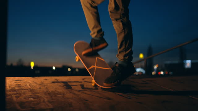 SLO MO Young Man Performing Shunts with Skateboard on Skate Park under Blue Sky at Night