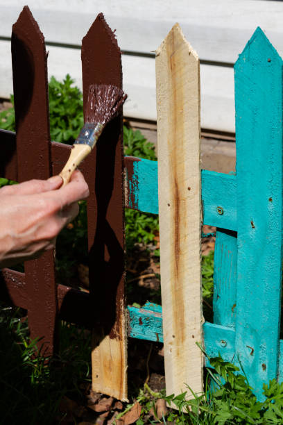 istock woman's hand paints a picket fence 1913763107