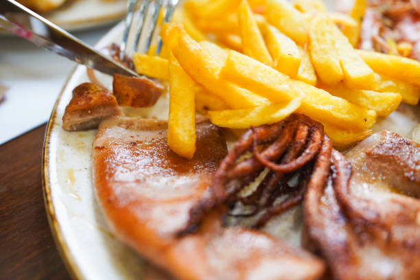 Fried calamari rings and fries served on a plate, partially eaten.
