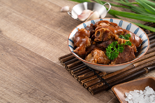 Close up of Taiwanese traditional food pork knuckle in a bowl on rustic table background.