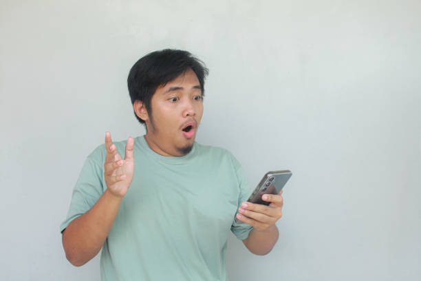 istock Young Asian man holding his handphone with a happy and wow expression. 1913875966