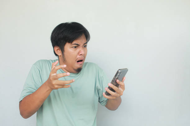 istock Young Asian man showing rage expression while see on his mobile phone. 1913880158