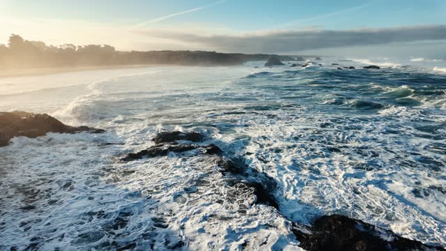 Slow motion drone shot of the Pacific ocean waves crashing on rocks on the coast of Fort Bragg, USA