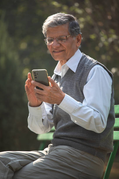 istock Old man texting mobile phone in park 1913982875