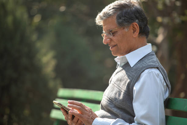 istock Old man texting mobile phone in park 1913983411