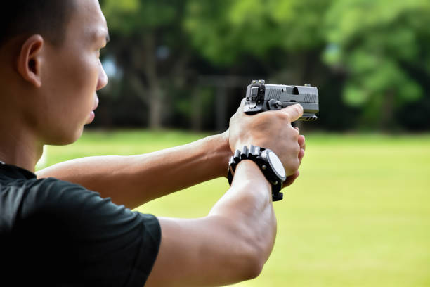 9mm pistol gun Asian young teens holding automatic black pistol in hands and ready to shoot, concept for shooting sport, robbery, safty, security, shooting training and bodygaurd. 20 mm caliber stock pictures, royalty-free photos & images