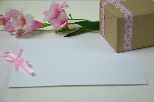 Gift or present box and flower on white table from above. Pastel color. Greeting card. Flat lay style. mockup, spring holiday, women's day, mother's day, easter