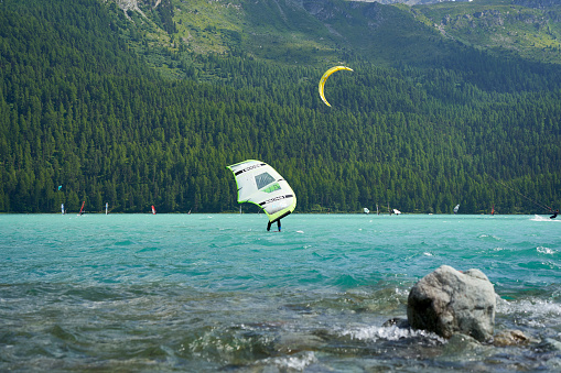 Engadin, Switzerland - July 16, 2023: Wing surfing and kite boarding on the lake. Lots of water sports and athletes on Lake Silvaplana. Swiss, Sankt Moritz, Engadin.