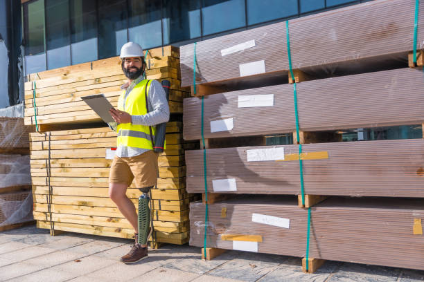 Relaxed engineer with prosthetic leg working in a construction site Engineer with prosthetic leg working outdoors with paperwork in a construction site leaning on a wall legs against the wall stock pictures, royalty-free photos & images
