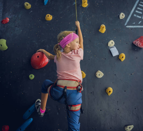 teenage boy climbing up the wall in outdoor adventure park passing obstacle course. high rope park