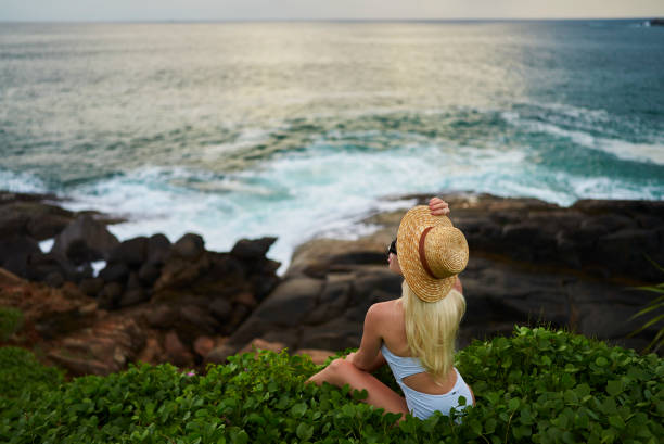 istock Tranquil scene as a woman in a straw hat observes the vast ocean from a lush cliffside, embodying mindfulness and serenity at a scenic coastal lookout, ideal for wellness and travel themes. 1914101773