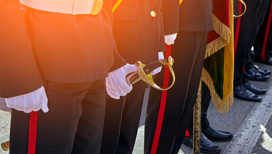Military honor guard with sword and weapon. A white glove holds a saber for Independence Day.