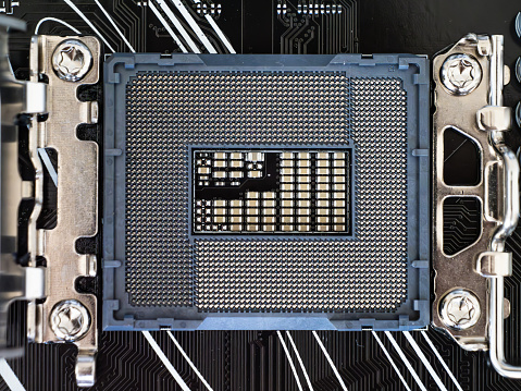 Closeup top view of a CPU socket on a black motherboard, semiconductor electronic industry, printed circuit board, computer science