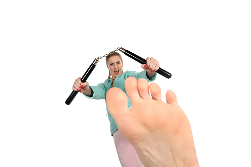 Woman kicking with nunchaku.