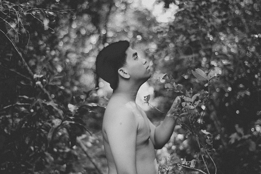 Boy blowing a flower in the park located in a rural part of the city.