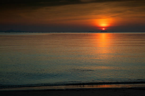Sunrise/sunset at sea, calm waves and orange sky.