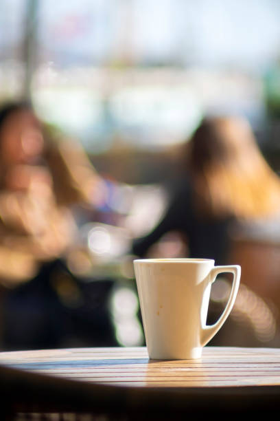 There is a cup of coffee on the table in front of people sitting in the cafe