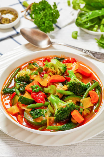 istock vegetable soup with green beans, broccoli, carrot, celery, spinach, cabbage, zucchini, tomatoes in white bowl on white wooden table 1914327977