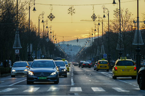 Budapest, Hungary - December 16, 2023: View from Hero square view to Andrassy street in the golden sunset light. Car's traffic on the foreground.