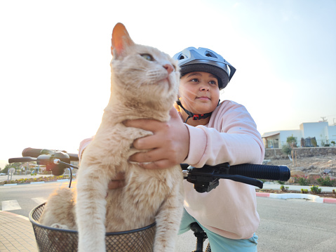 Close-up image of a Nine-year-old girl riding her bicycle with her cute domestic cat.