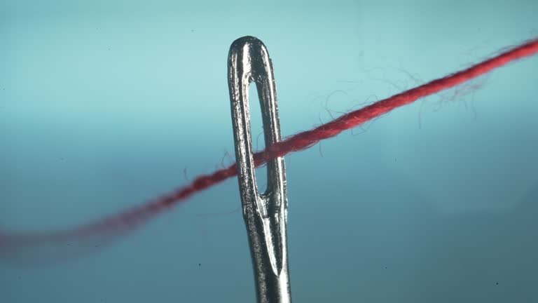 Running a red thread through a needle eyelet