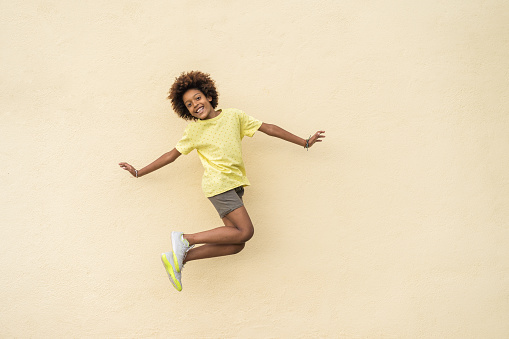 Happy young African American boy smiling and enjoying while jumping in the air. Freedom and childhood concept.