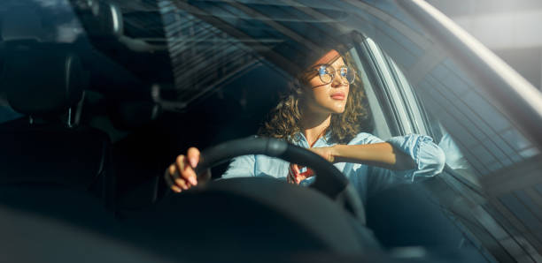 woman sitting in a car - conducir fotografías e imágenes de stock