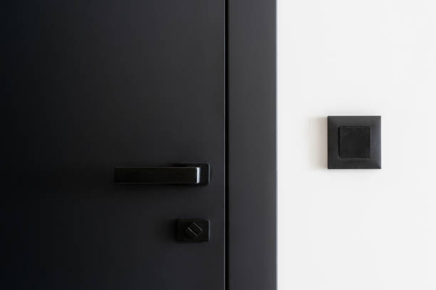 istock Closeup on light switch on white wall near closed grey door with metal handle 1914469410
