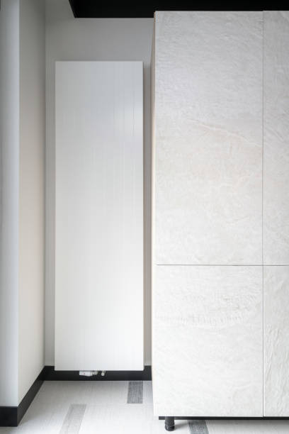 istock White heating radiator install on wall next to wardrobe in apartment. 1914469635