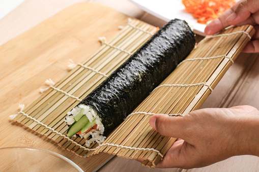 Close Up View Process of Preparing Rolling Sushi/Gimbap/Kimbap. Nori and White Rice. Chef's Hands Touch Roll Rice. Chef Finish Making Kimbop or Cooking
