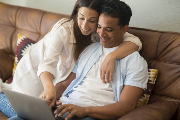 istock Young couple moving to a new home relaxing sitting on the sofa using computer laptop, smiling happy for moving to new apartment 1914499504
