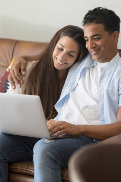 istock Young couple moving to a new home relaxing sitting on the sofa using computer laptop, smiling happy for moving to new apartment 1914502104