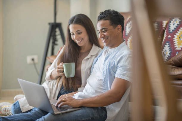 istock Young couple moving to a new home relaxing sitting on the sofa using computer laptop, smiling happy for moving to new apartment 1914503158