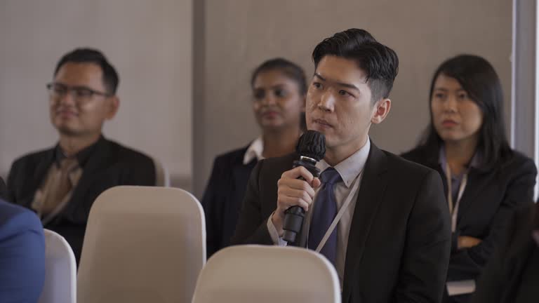 unsatisfied Asian Chinese entrepreneur asking question at business conference participants in workshop