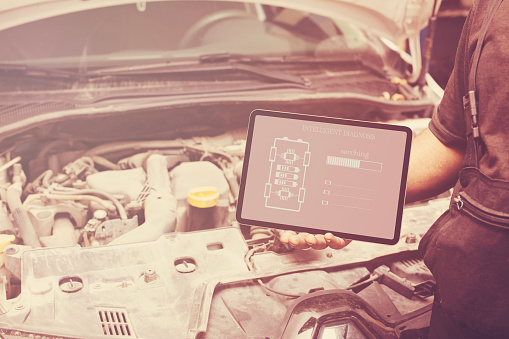 Mechanic using tablet checking up on car engines parts for fixing and repair