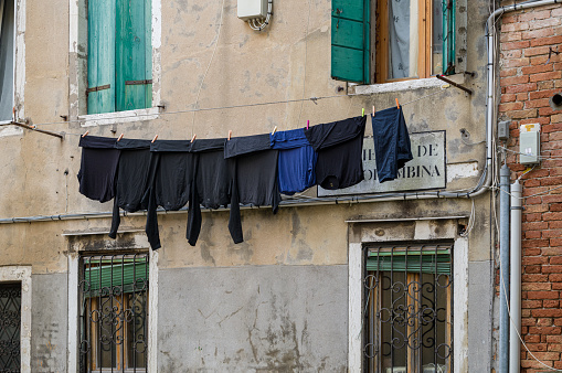 A washing line with black laundry, as it is hung on the walls of old houses in Italy.