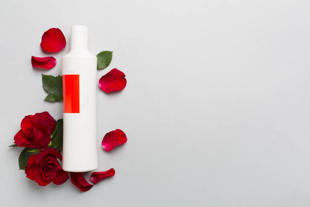 istock Cosmetic bottle and red roses on color background, top view 1914534835