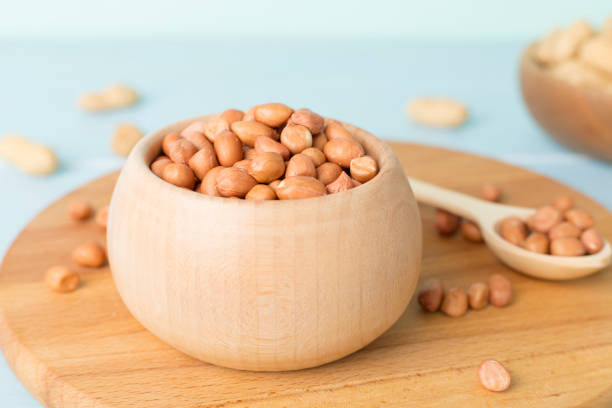 istock Peeled and unpeeled peanuts on wooden table 1914535908