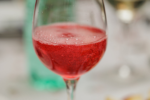 macro view of a wineglass filled with gingerino, a red, sweet and sparkling drink, used in aperitives