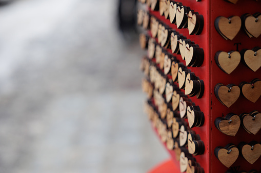 macro view of small heart-shaped wooden decorations being sold at a local market. blurred background with gray and white shades