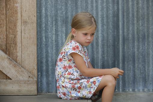 Annoyed little girl sitting on the street steps