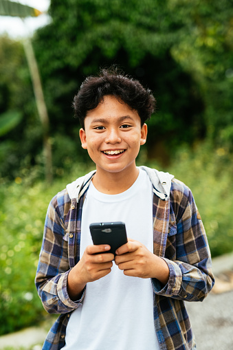 Malaysian boy using smart phone and smiling