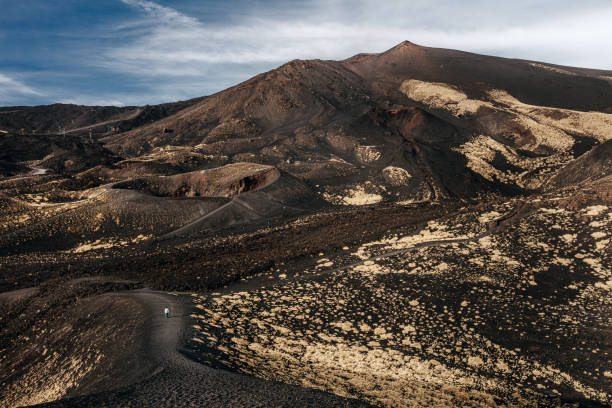 istock Etna volcanic landscape with a small human figure walking through. 1914614074