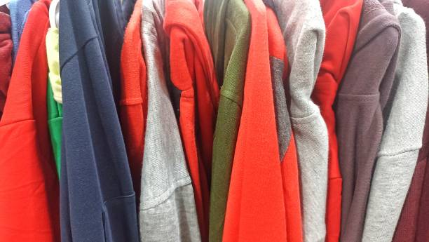 istock Warm sweaters. Autumn, winter clothes. Metal rack with various sweaters on hangers placed in modern fashion boutique 1914621874