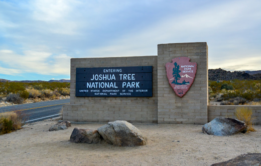 Death Valley, California, USA- March 2023: Sign at the entrance of  Death Valley National Park, in Mojave desert, California USA. with view of road and mountains
