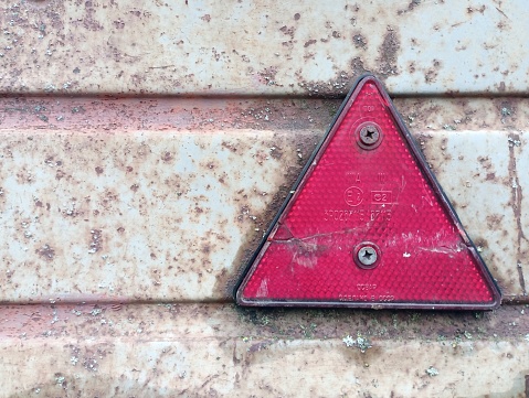 Triangular light reflector on board of a car trailer. Reflector for indicating the dimensions of the vehicle.