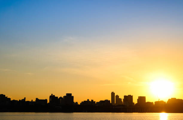 istock Skyscape just before sunset - sun visible through clouds, skyline in black silhouette 1914640092