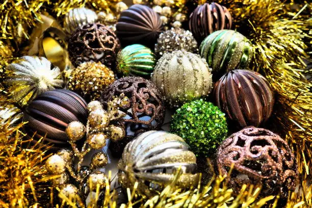 New Year's Christmas balls, tinsel and decorations close up. A lot of decoration of golden, brown, yellow, green. Striped Christmas balls. Festive beautiful colorful background. Home holidays design