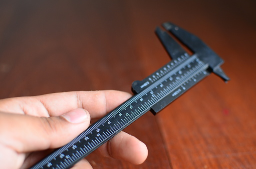 vernier calipers measuring metal nut,on drawing background