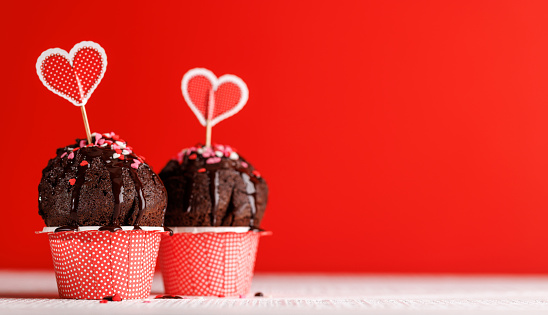 Cupcake love: Heart-themed treats on a vibrant red backdrop with copy space for your Valentines day greetings